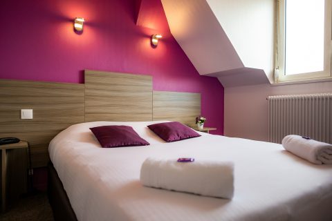 Chambre simple 1 personne violette et blanche vue sur le lit