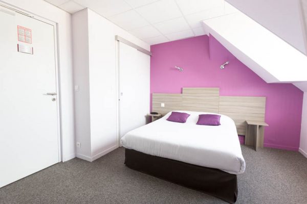 chambre simple violette et blanche, vue sur le lit