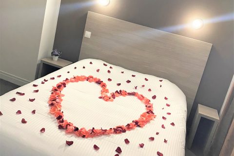Chambre double confort, coeur en pétales sur le lit pour la saint valentin