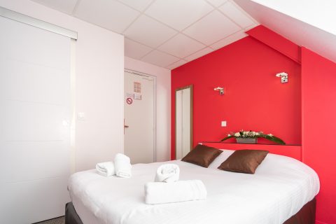 chambre double confort rouge et blanche, vue sur le lit